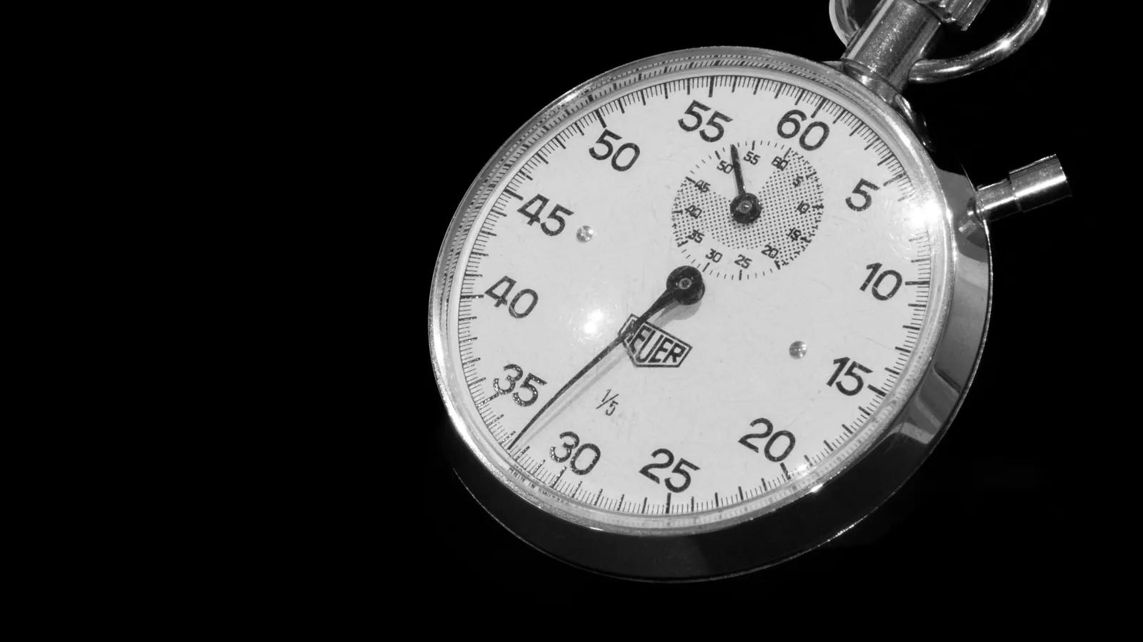 A mechanical stopwatch dial photographed close up on a dark ground