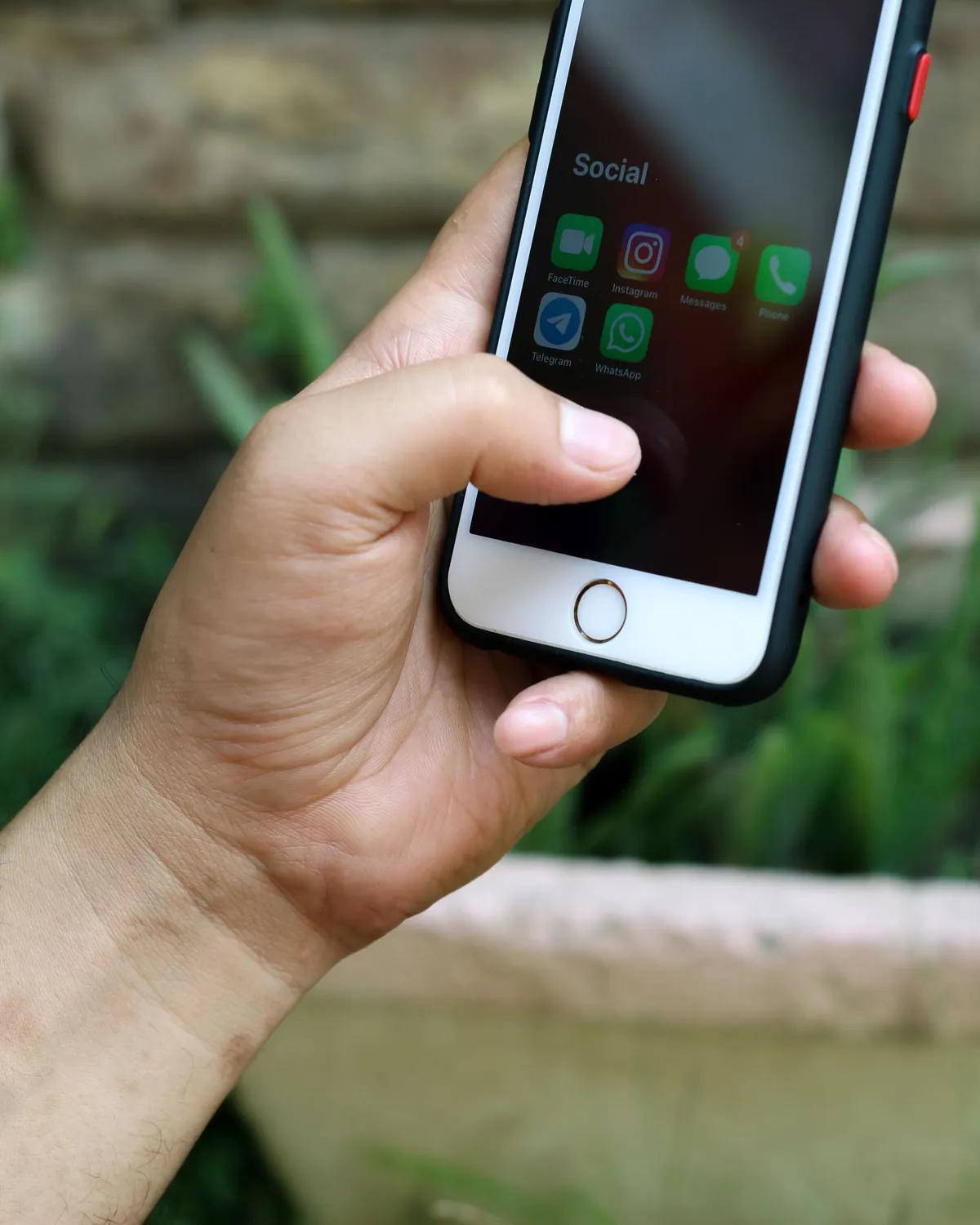 A phone held mid-scroll showing social apps, demand that has to be created