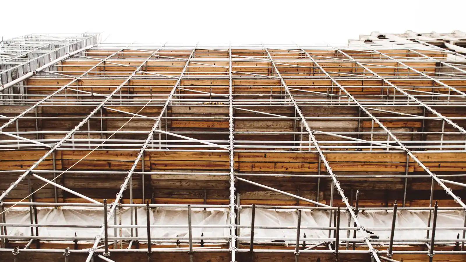 A building mid-construction behind scaffolding, a structure not yet load-bearing